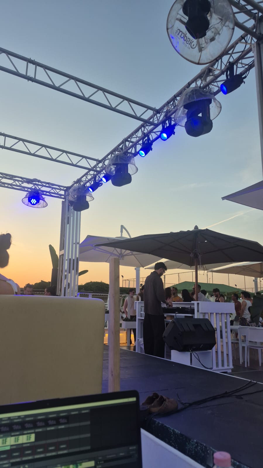 Struttura con luci accese sopra una postazione musicale all’aperto al tramonto