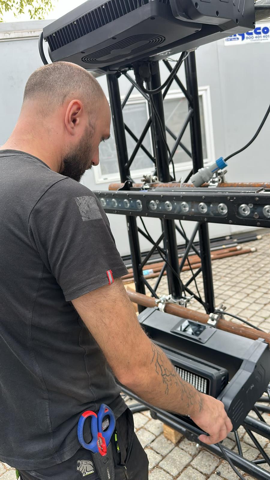 Tecnico impegnato nella preparazione di un proiettore su una struttura